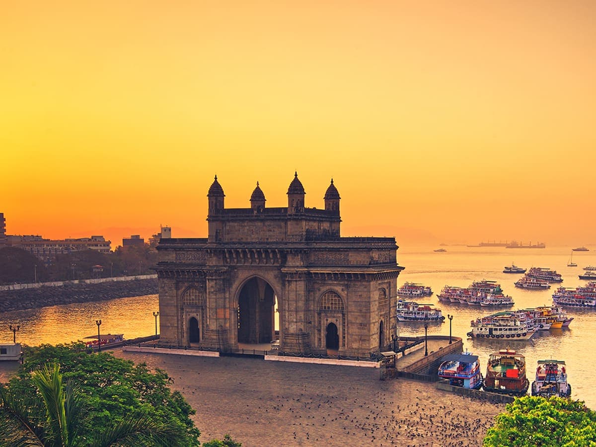 The Gateway of India in Mumbai at sunrise, boats on the harbour